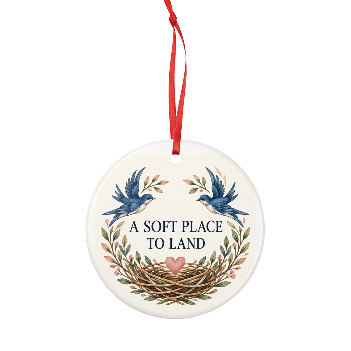Round ceramic hanging ornament showing two blue birds, botanical sprigs, a nest and A Soft Place to Land lettering.