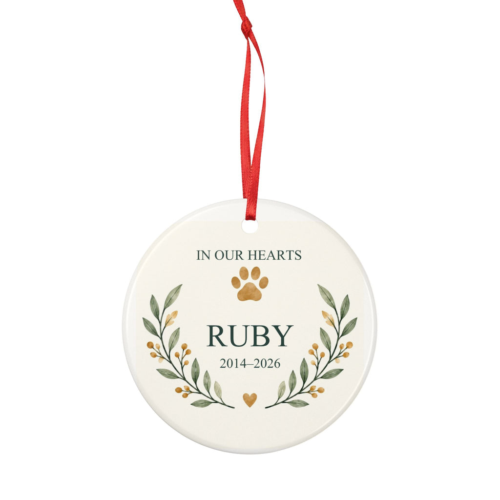 Round ceramic hanging ornament showing paw print and botanical branches around the sample name Ruby and sample years 2014–2026.