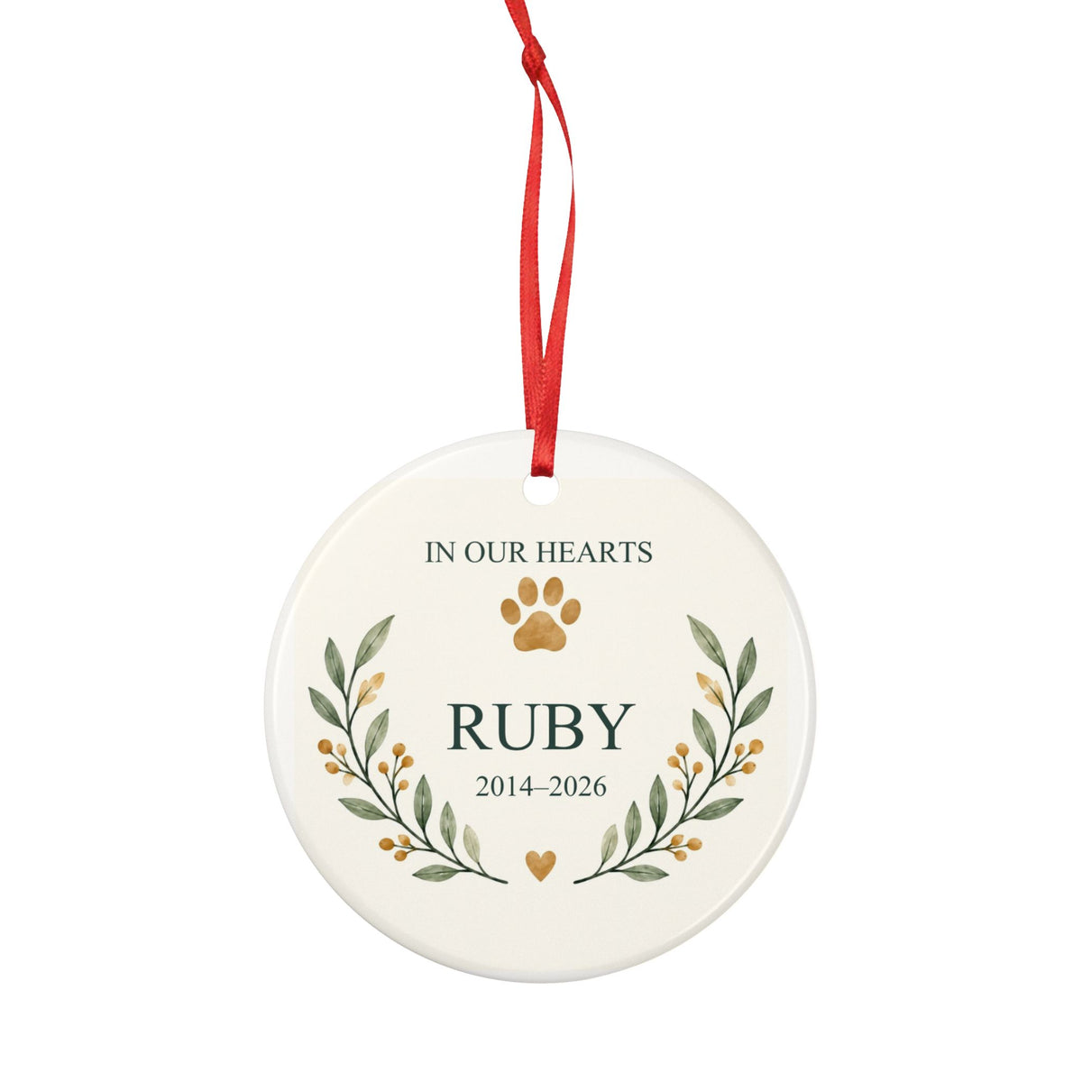 Round ceramic hanging ornament showing paw print and botanical branches around the sample name Ruby and sample years 2014–2026.