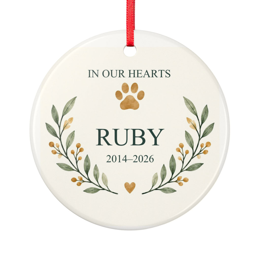 Round ceramic hanging ornament showing paw print and botanical branches around the sample name Ruby and sample years 2014–2026.