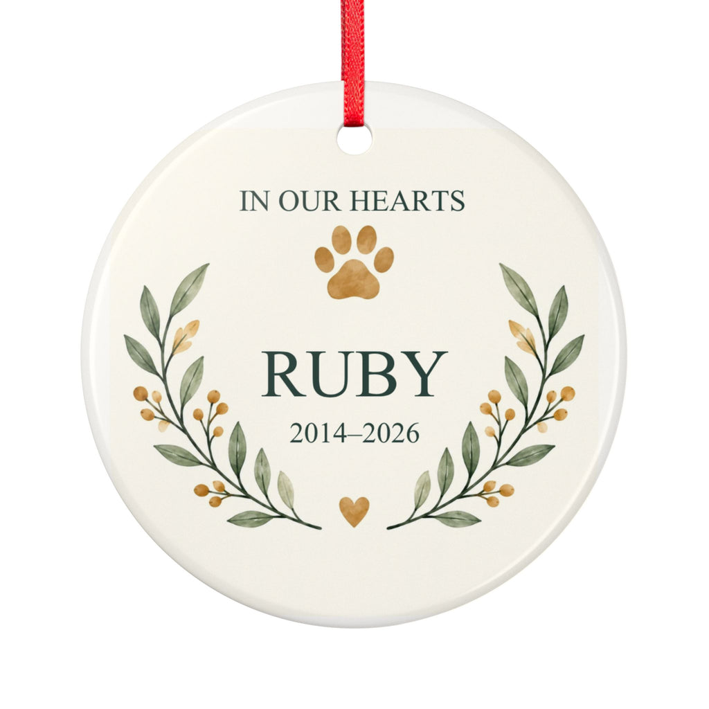 Round ceramic hanging ornament showing paw print and botanical branches around the sample name Ruby and sample years 2014–2026.