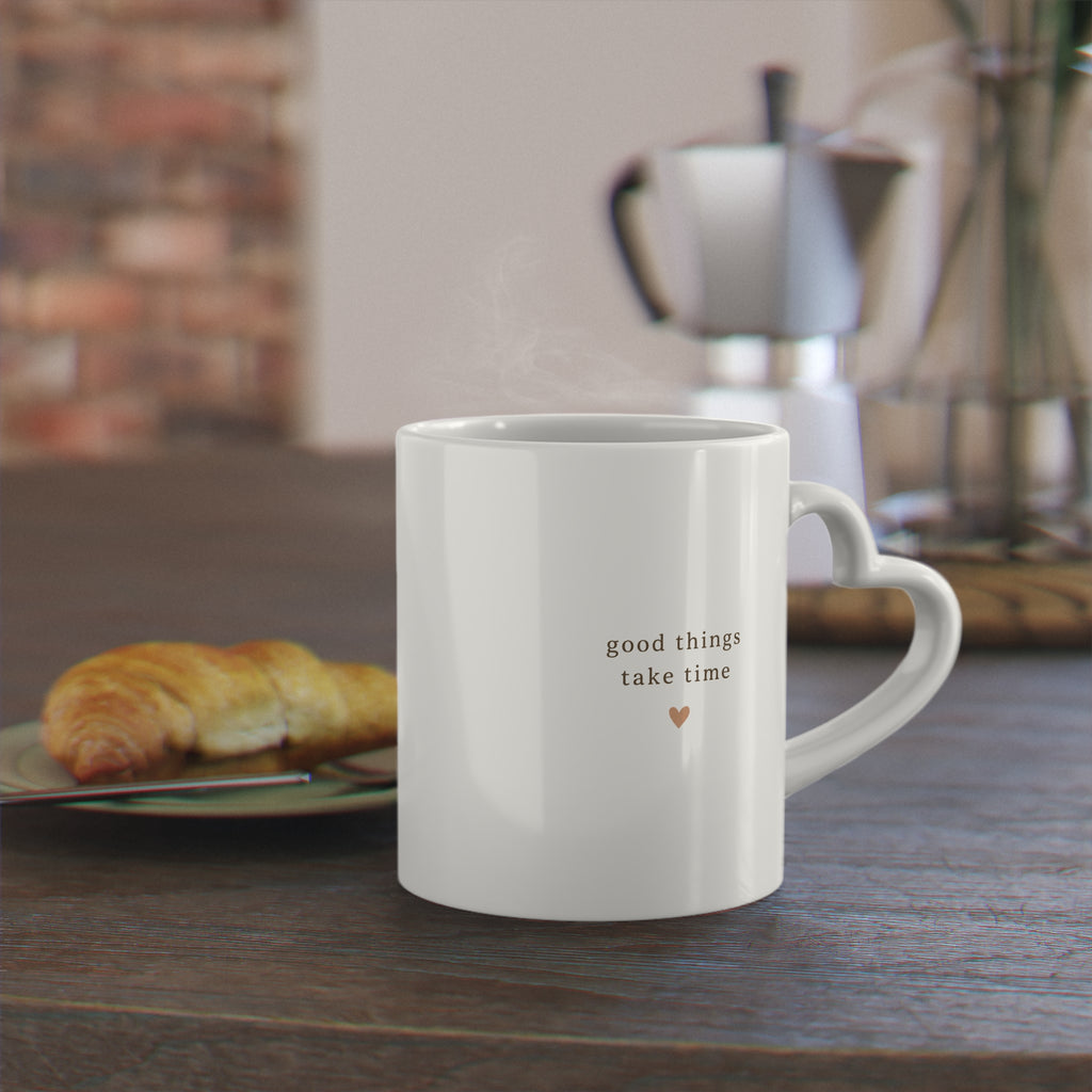 Good Things Take Time heart-handle mug beside a croissant and coffee pot