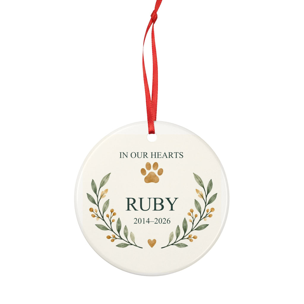 Round ceramic hanging ornament showing paw print and botanical branches around the sample name Ruby and sample years 2014–2026.