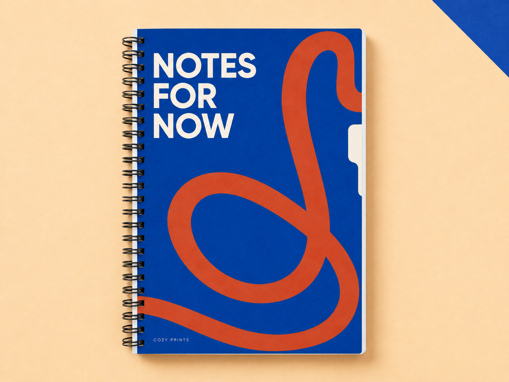 Notes for Now A5 wirebound notebook with a blue and orange abstract cover on a warm apricot backdrop.