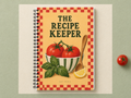 The Recipe Keeper A5 wirebound notebook with a checked border, tomatoes and bowl on a sage and cream backdrop.