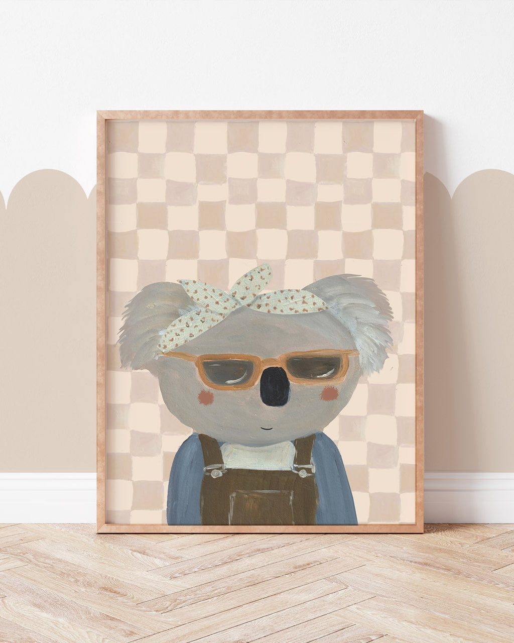 Bring Me Sunshine print showing a koala in sunglasses, a bow headband and dungarees against peach checks, displayed in a frame.