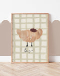 Croissant art print with a smiling beret-wearing pastry, Bonjour lettering and sage checks, displayed in a wooden frame.