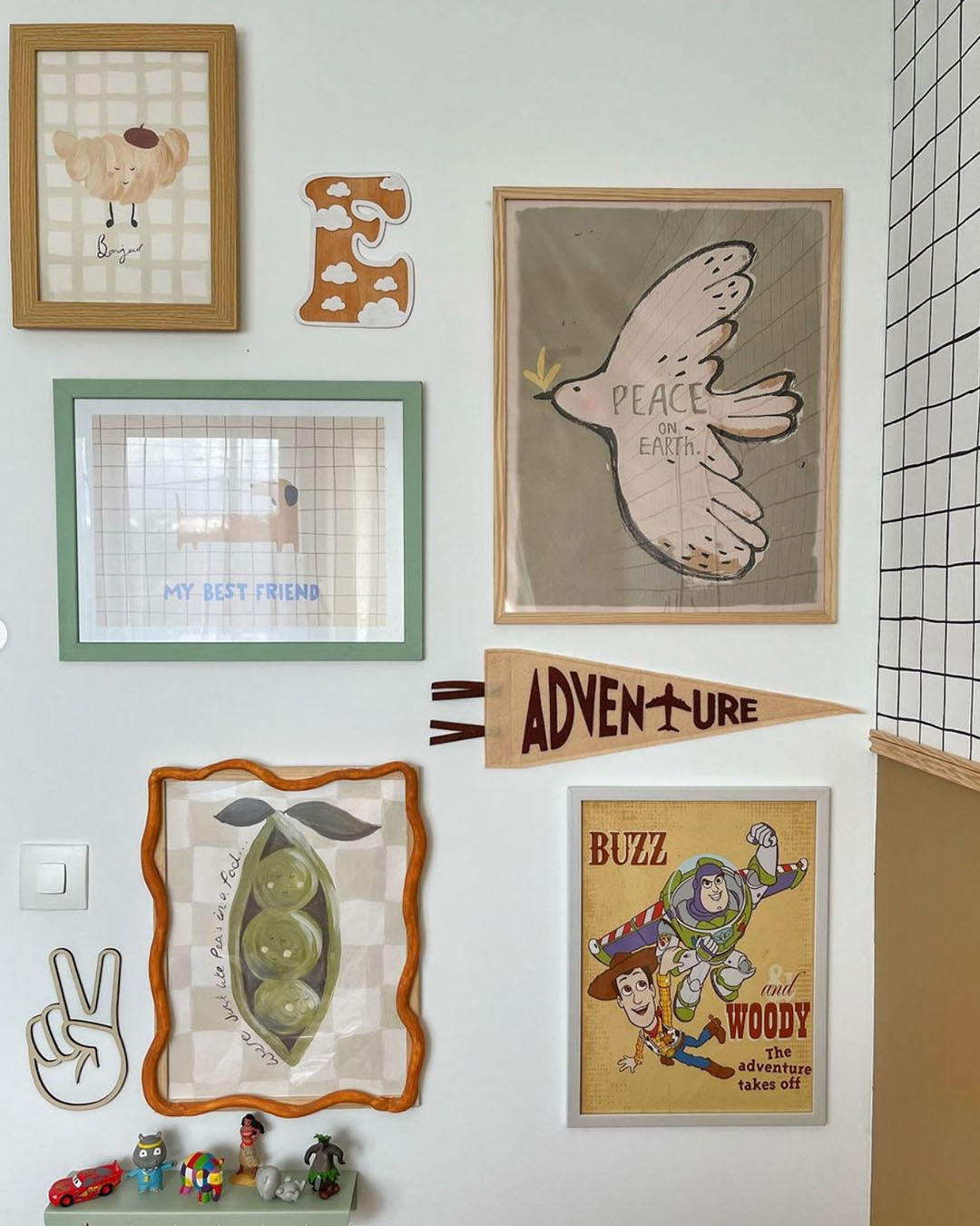 Croissant print at the top left of a children's gallery wall with animal artwork and an Adventure pennant.
