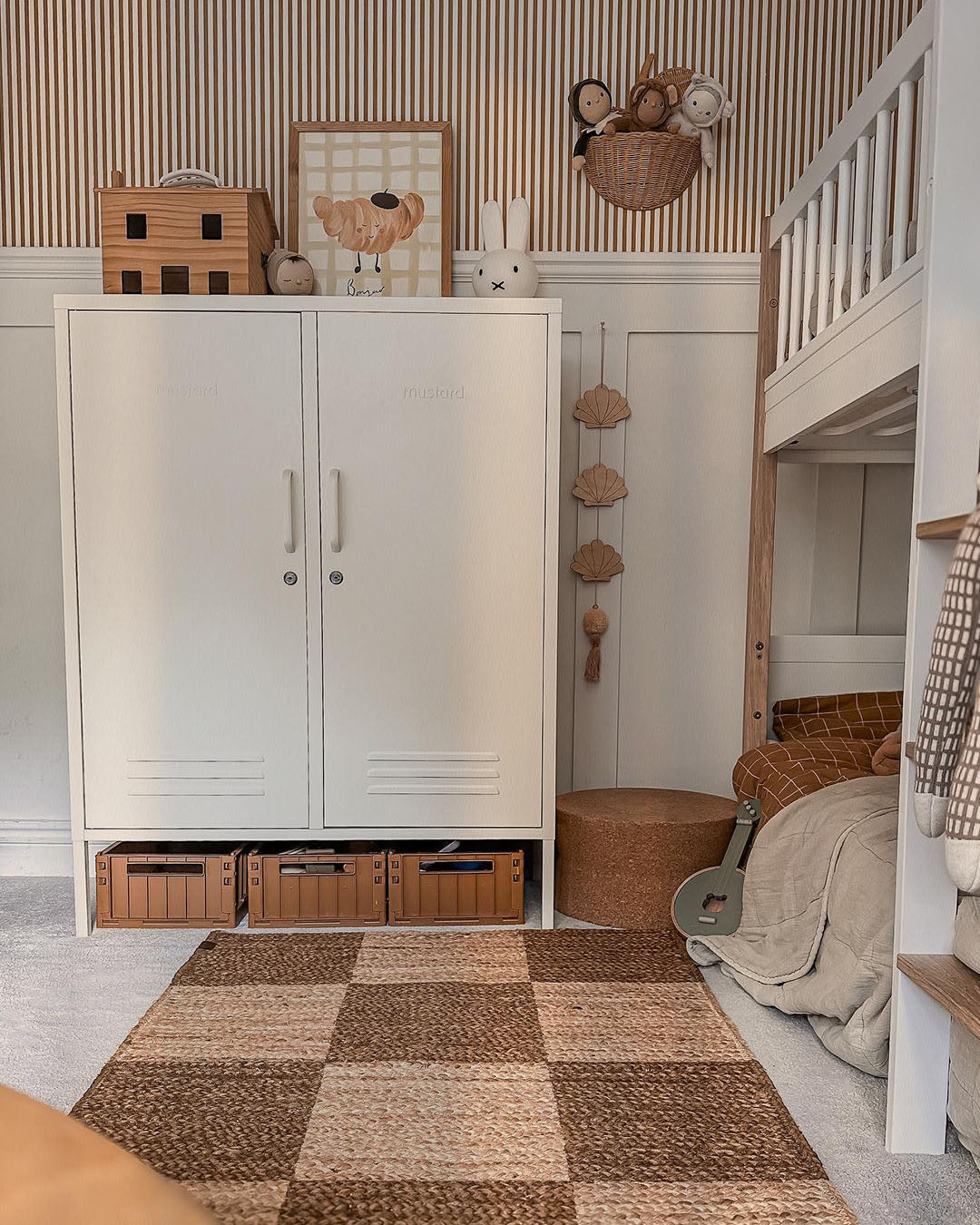 Croissant print displayed on top of a white nursery wardrobe beside bunk beds and a checked rug.